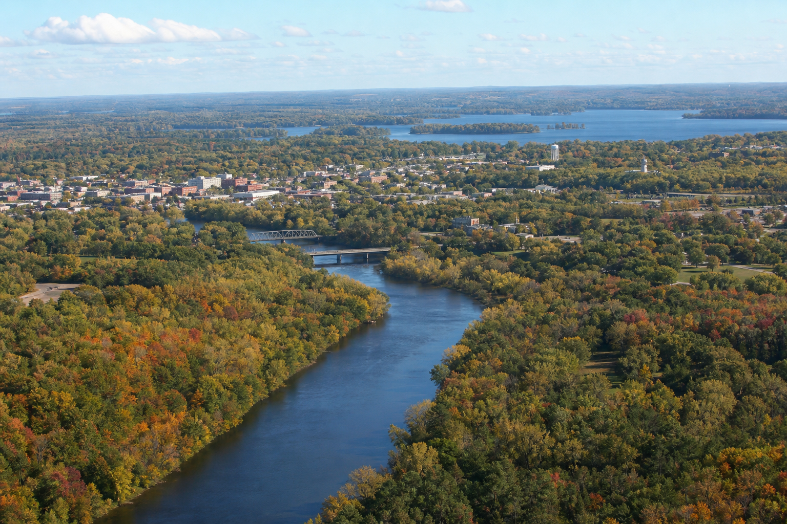Elevated view over a wooded Mississippi River corridor, a modest city and distant lakes